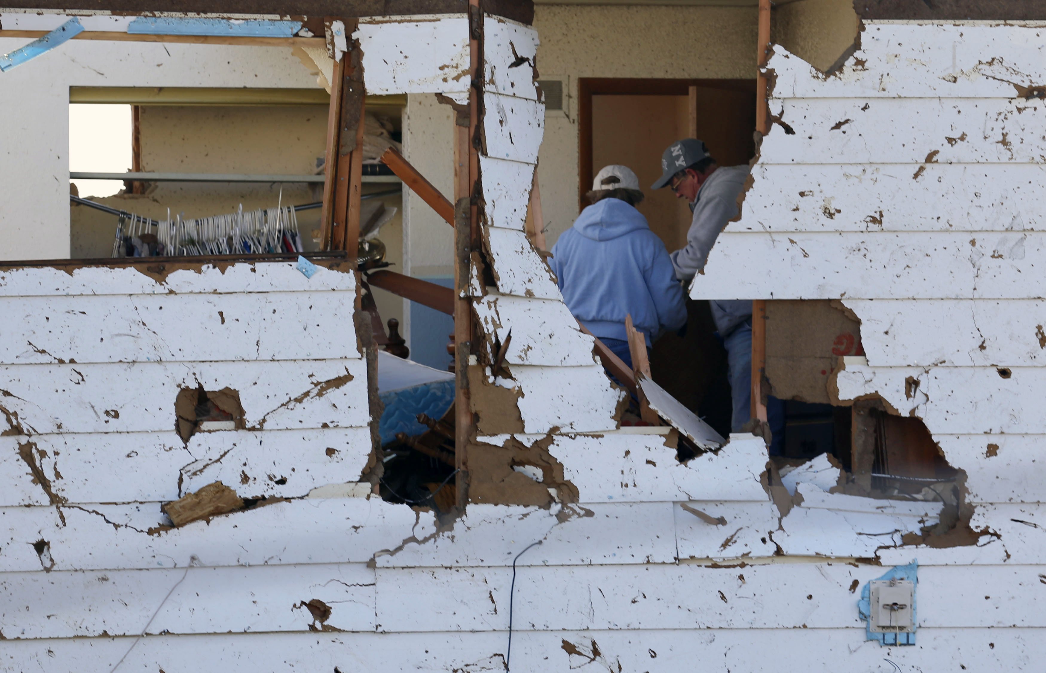 People are seen in a house going through belongings in the destruction caused by a tornado that touched down in Washington, Illinois