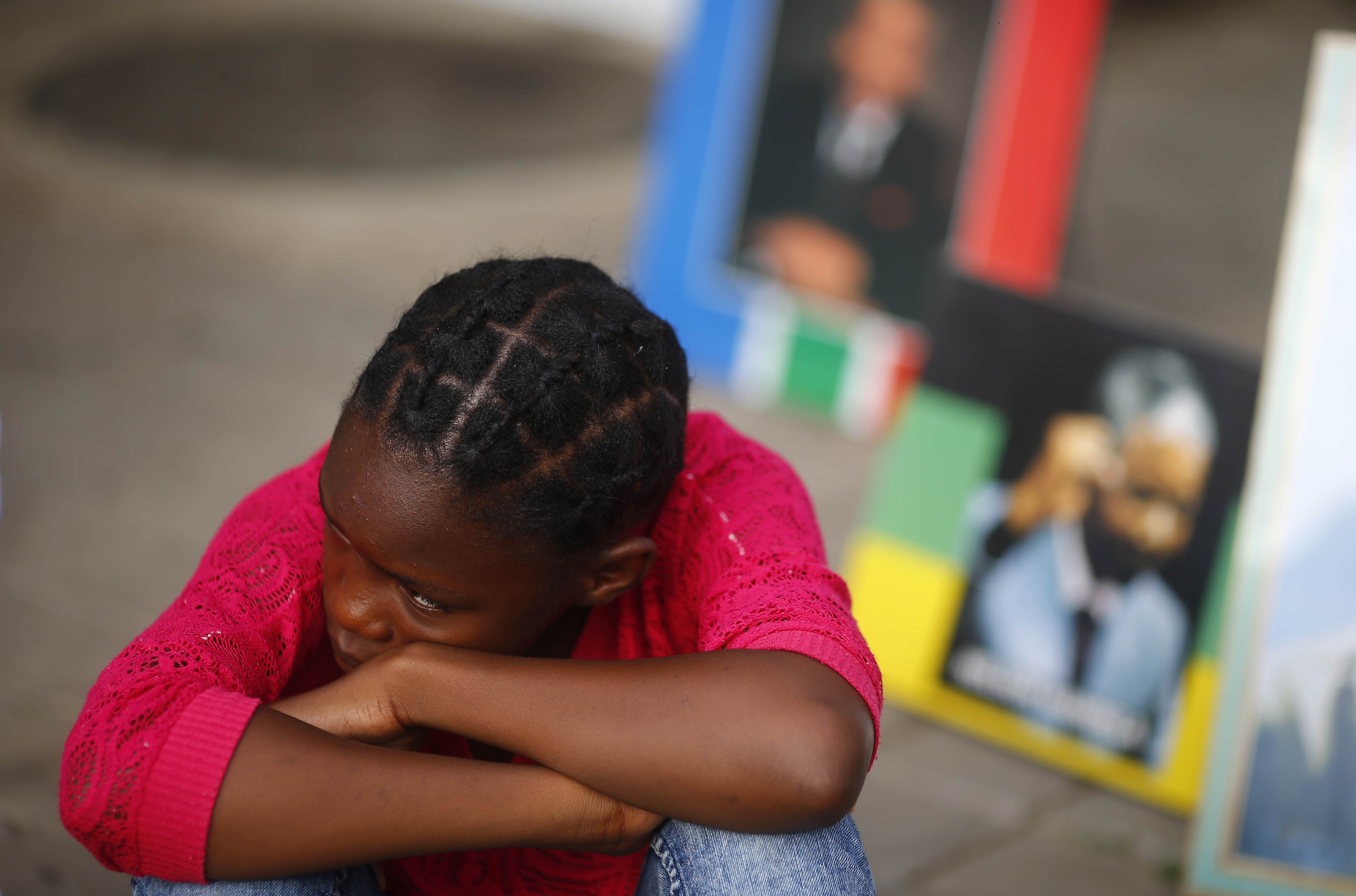 A young girl sits on the entrance of Vilakazi street near Mandela house in Soweto