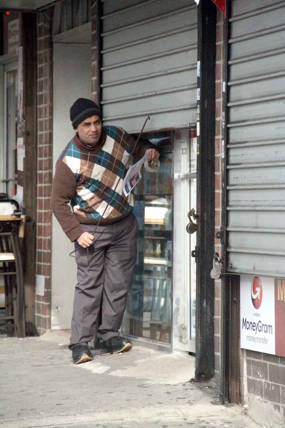Abdul Razak Al-Kabili, 42, shuts the roll-down gates of the Smoke Shop at 3200 Bainbridge Avenue.--Photo by David Greene