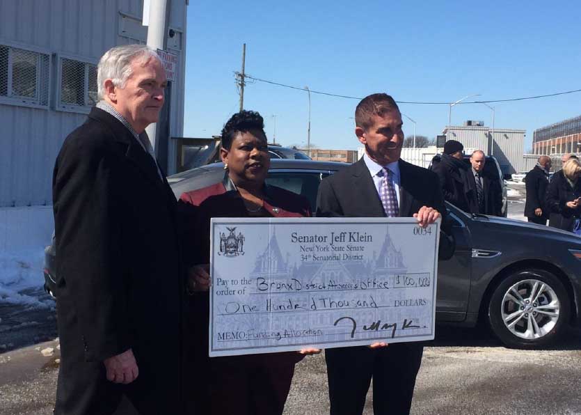 DOC Commissioner Joseph Ponte, DA Clark and State Senator Jeff Klein pose with a mock-up check outside the Rikers Island Prosecution Bureau.