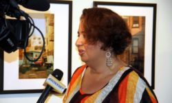 Longwood photographer Clarisel Gonzalez is interviewed next to some of her photographs featured in a new exhibit. Photo by David Greene