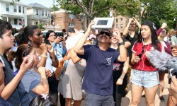 A crowd gathers around a man who designed his own special eclipse viewing glasses in Pelham Bay.--Photo by David Greene