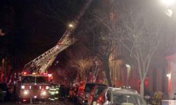 Firefighters used tower ladders and portable ladders to access the first three-floors after a deadly fire at 2363 Prospect Avenue in the Belmont section.--Photo by David Greene