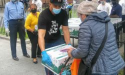 Bronx Borough President Ruben Diaz Jr. carefully places a box of food on this woman's wagon for her to take home.